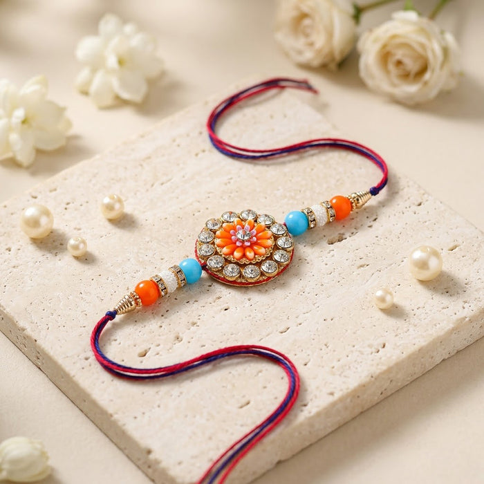 Circular Crystal Encrusted Floral Emblem Orange Accent Rakhi
