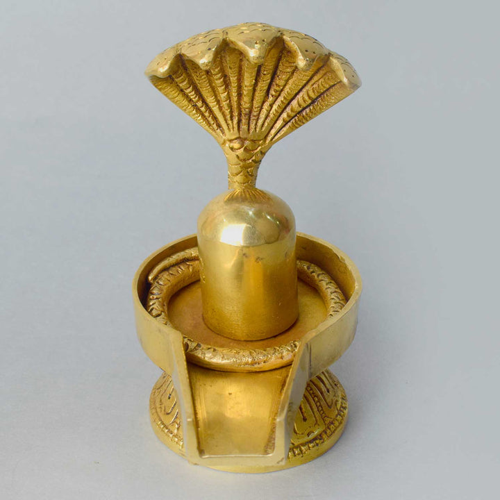 4.7 Inch Handcrafted Brass Shivling with Sheshnaag coiled gracefully around the sacred symbol of Lord Shiva, representing protection, eternity, and divine energy. No.1 Brass Idol Store www.satvikstore.in 